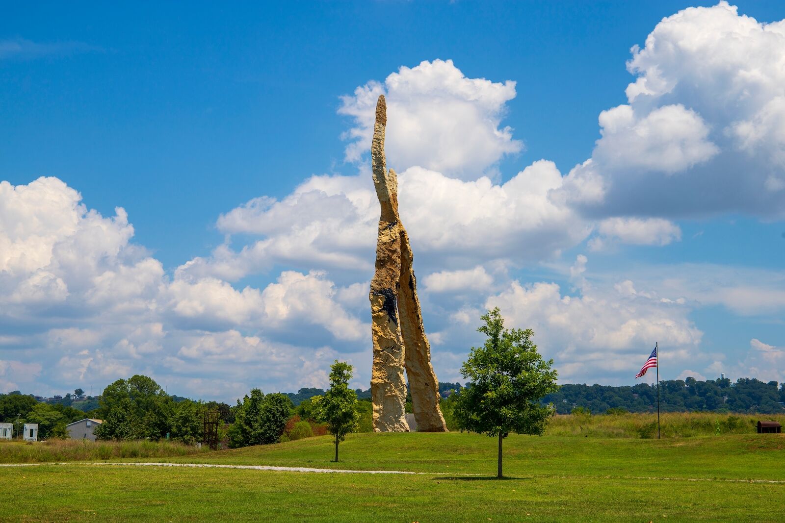 a gorgeous summer landscape in the park with sculptures and lush green trees, grass and plants with a gorgeous blue sky and powerful clouds at Sculpture Fields at Montague Park in Chattanooga