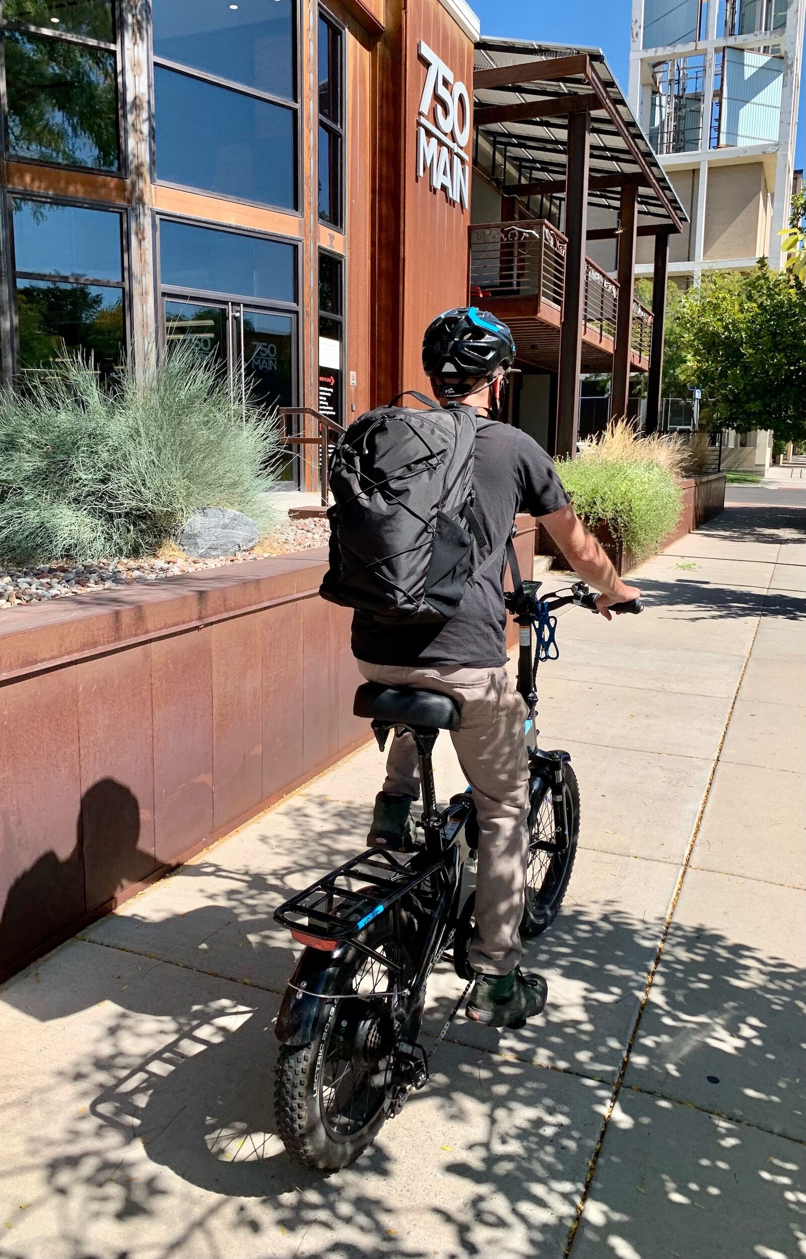 man riding bike with patagonia refugito backpack