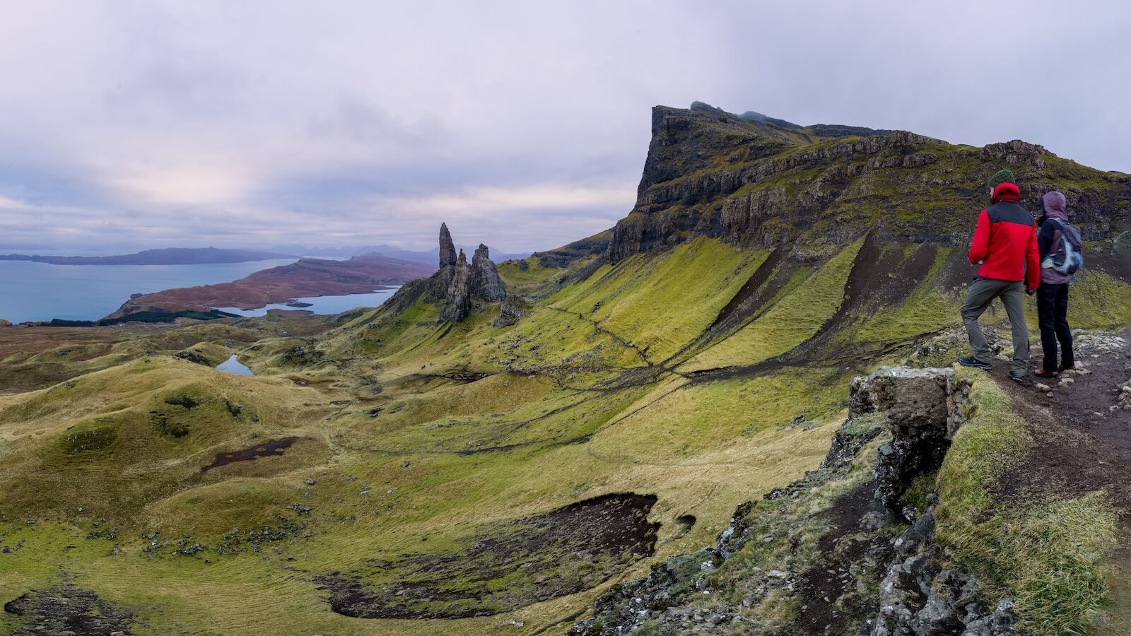 Couple hand in hand in rugged volcanic landscape around Old Man of Storr, Isle of Skye, Scotland