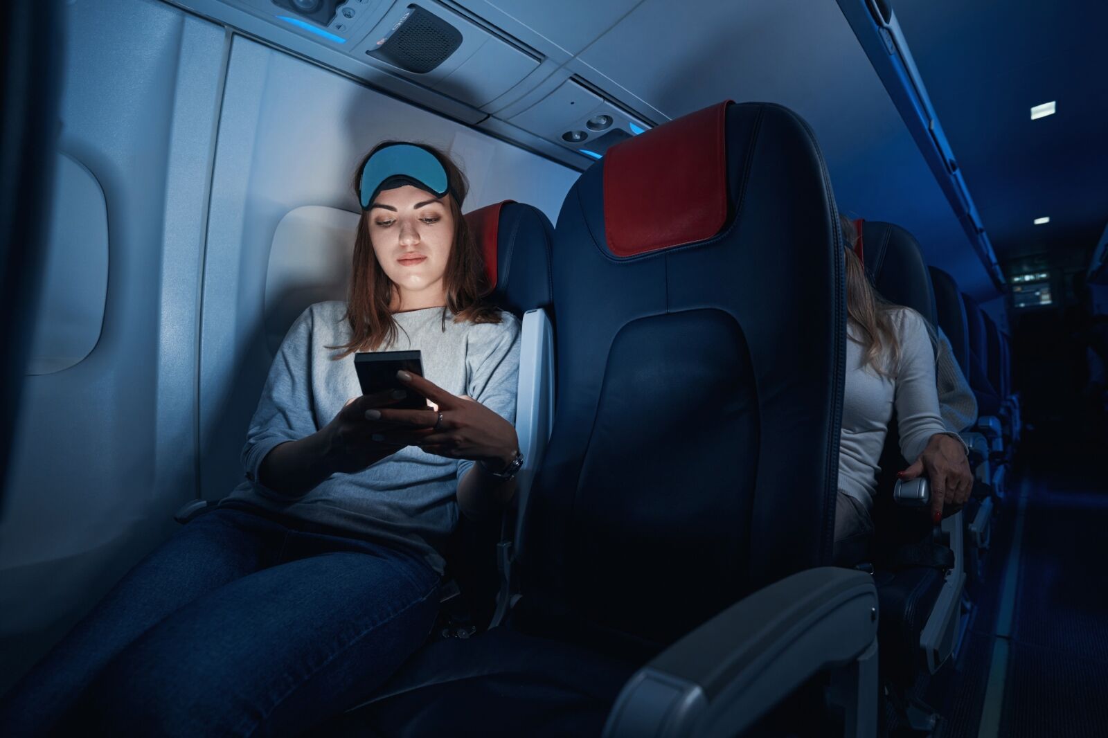 Female clicking her smartphone during night flight 