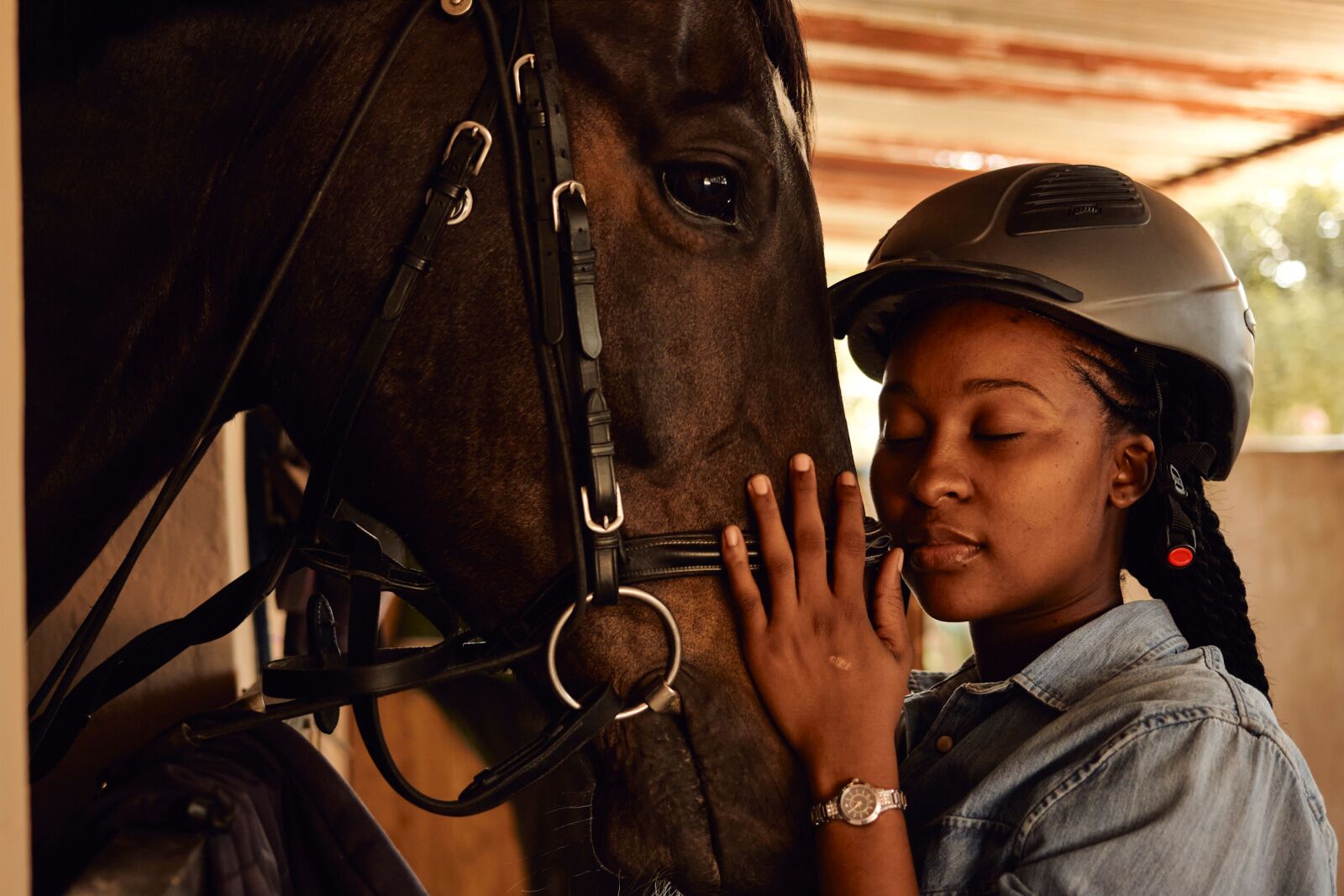 woman in barn with helmet petting horse nose - equine therapy