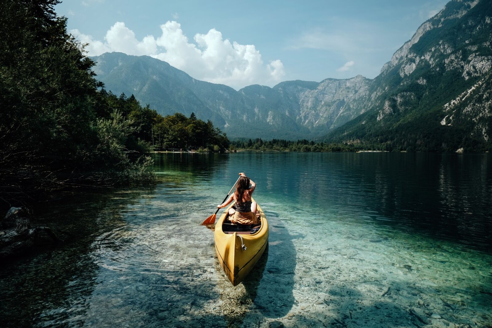 Young woman canoeing in the lake bohinj on a summer day one of the best lakes in Europe