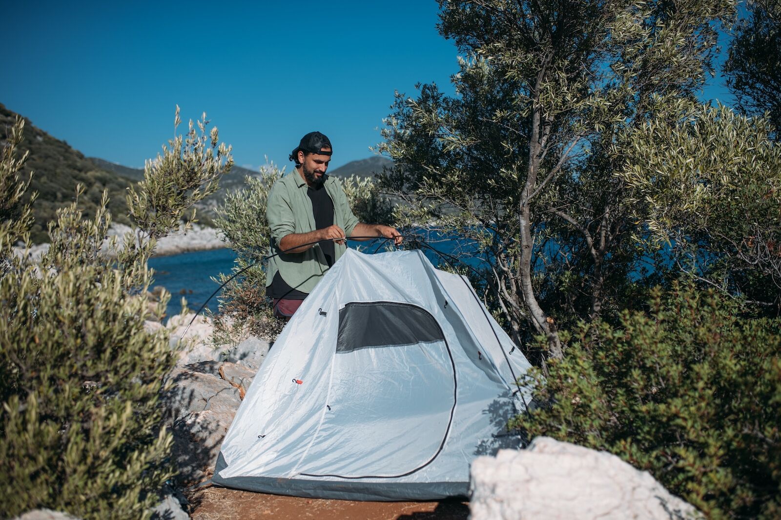 rent camping gear - man with tent and lake