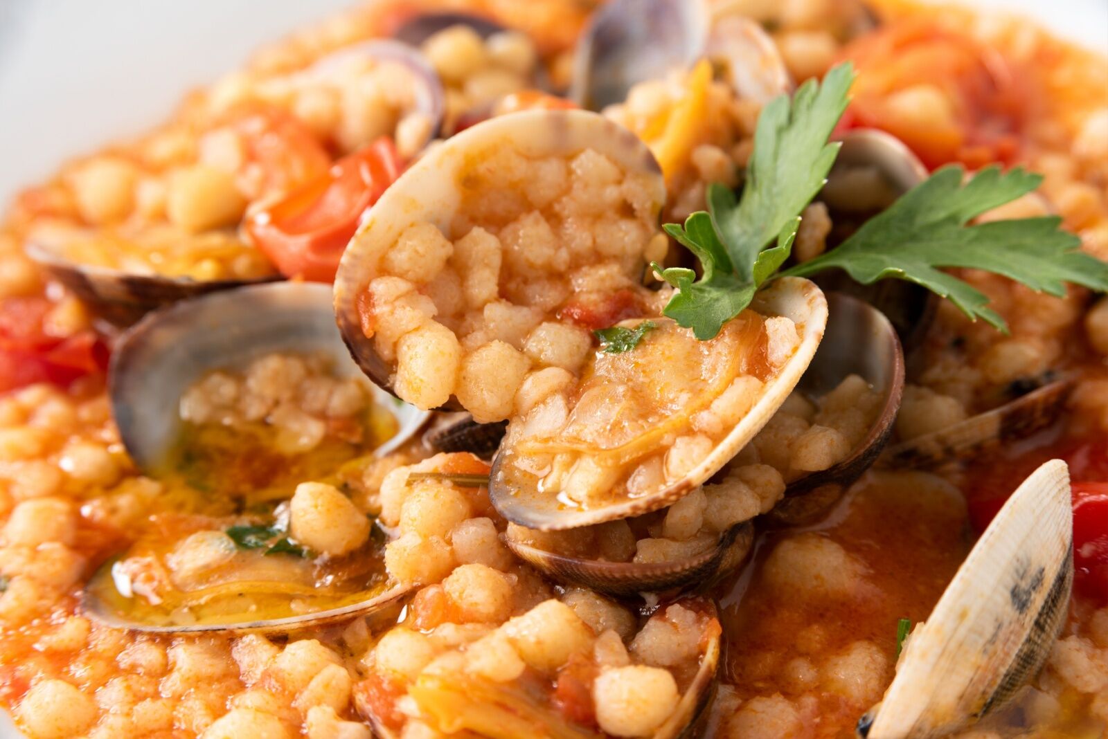 Closeup of delicious fregola with clam and tomato sauce, typical Sardinian Food