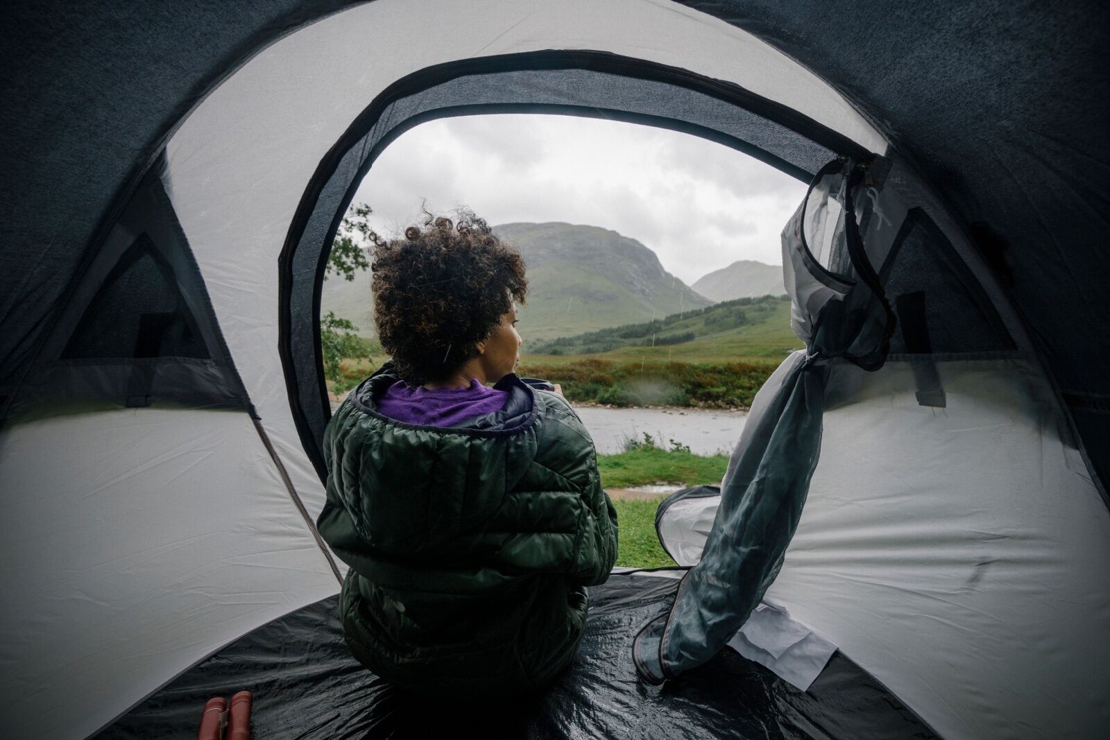 woman rain camping in tent - hipcamp weather guarantee 