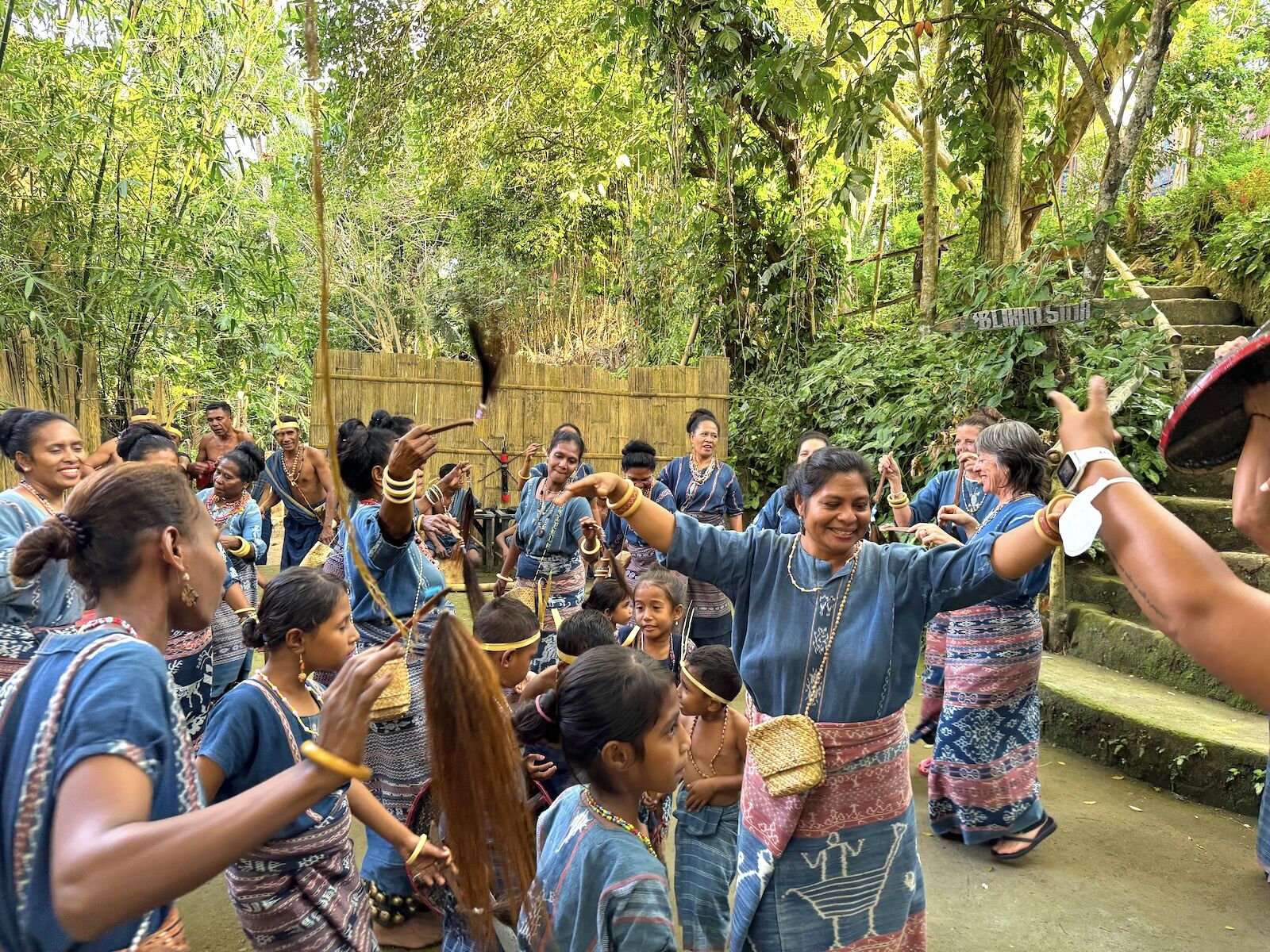 SeaTrek indonesia sailing guests and locals dancing together during a village visit. 