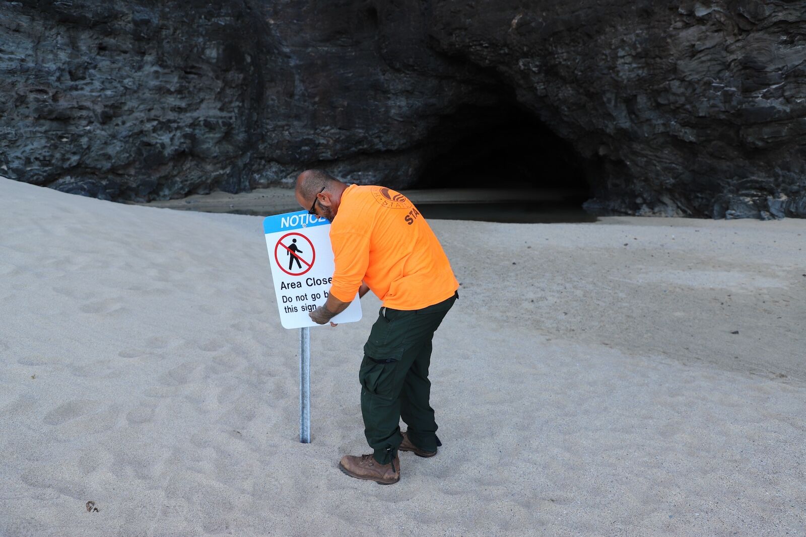 Kalalau Trail closure hawaii norovirus - man mounting closed sign