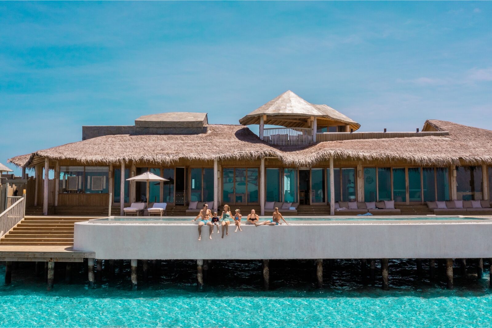 Family sitting by pool at Soneva Secret, Maldives a 2024 new hotel