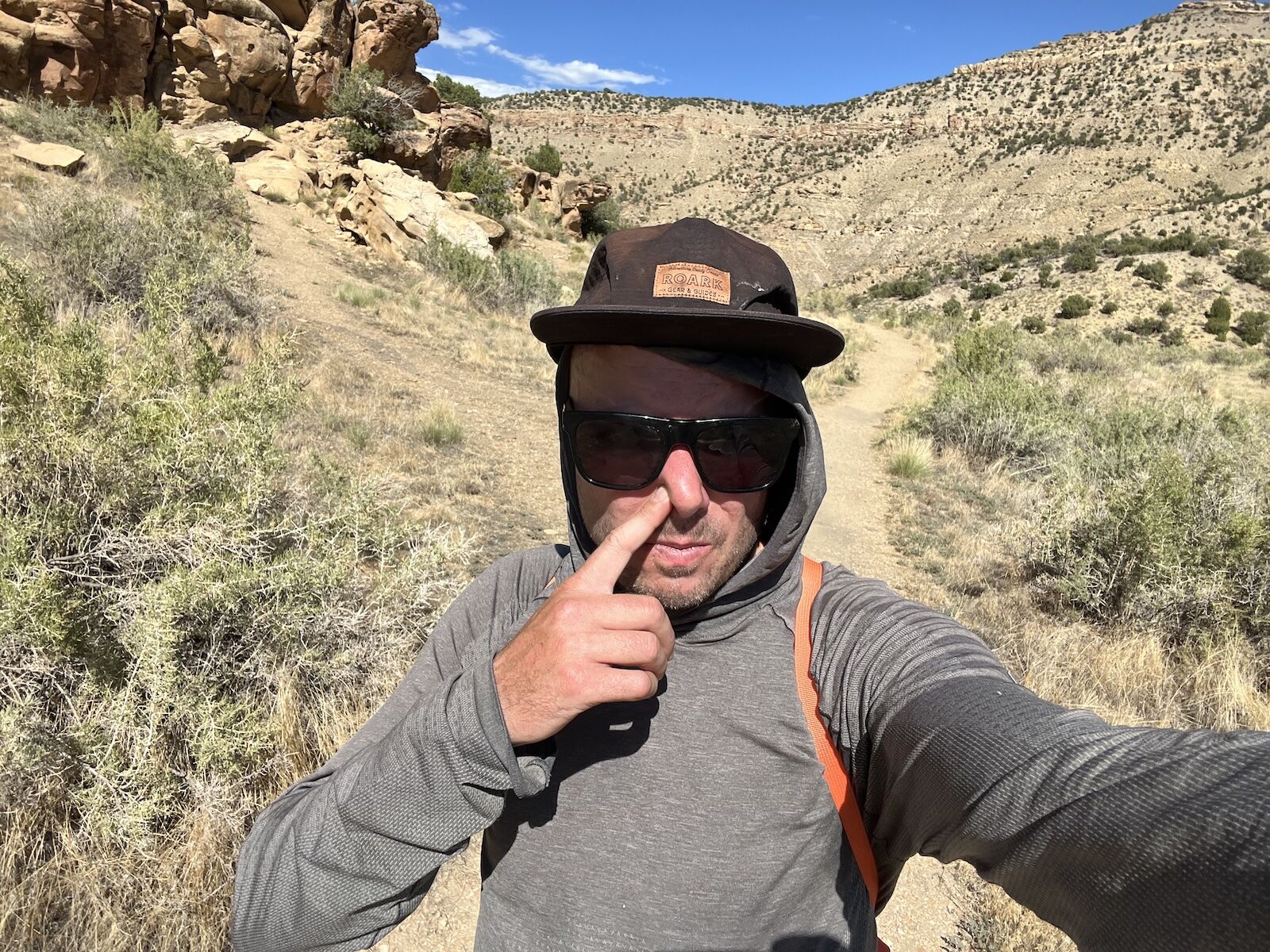 man plugging his nose while hiking