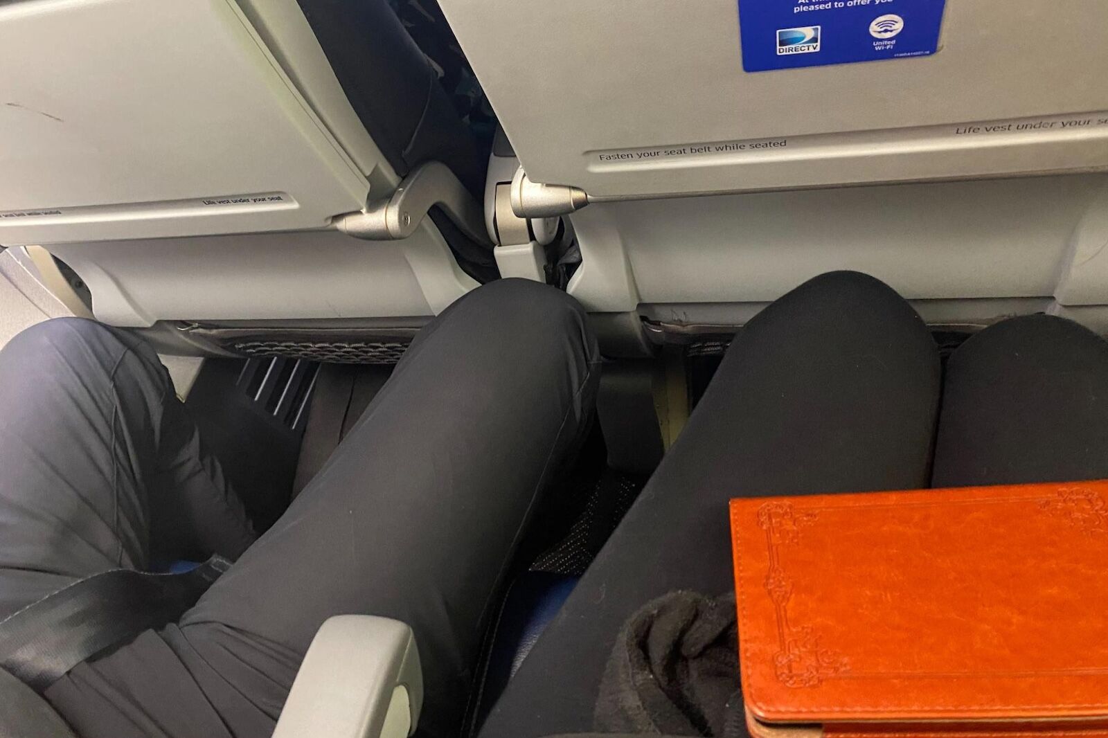 man spreading his legs in the seat on a flight