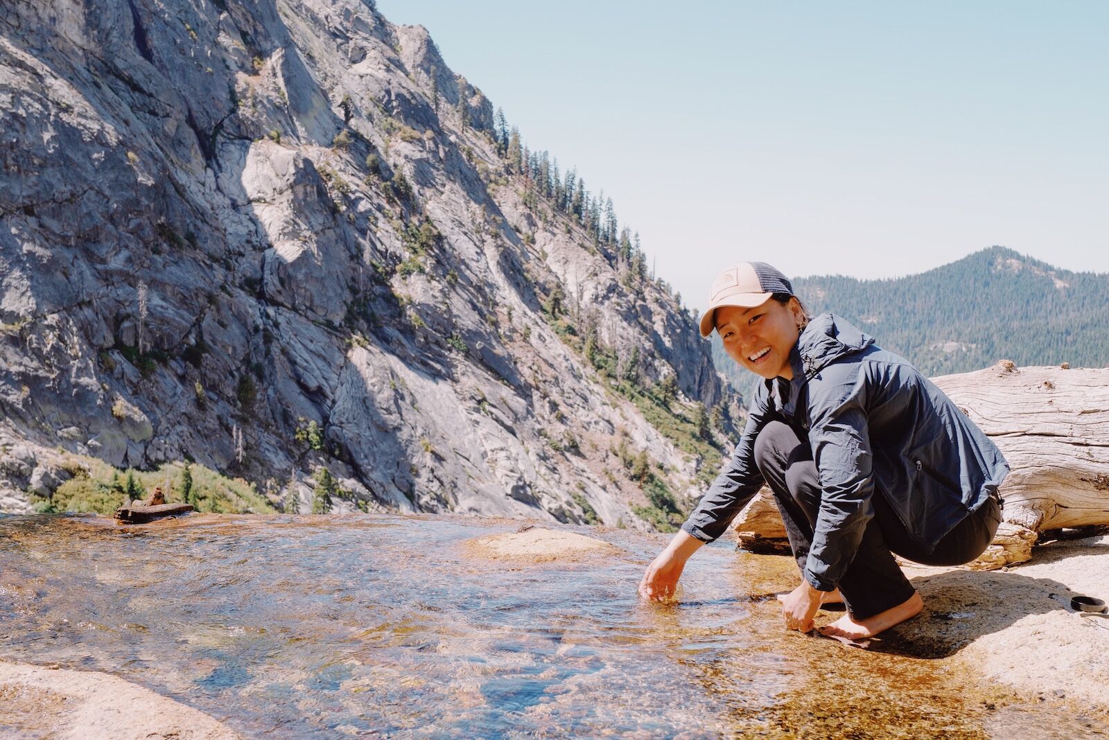 woman by stream in mountains