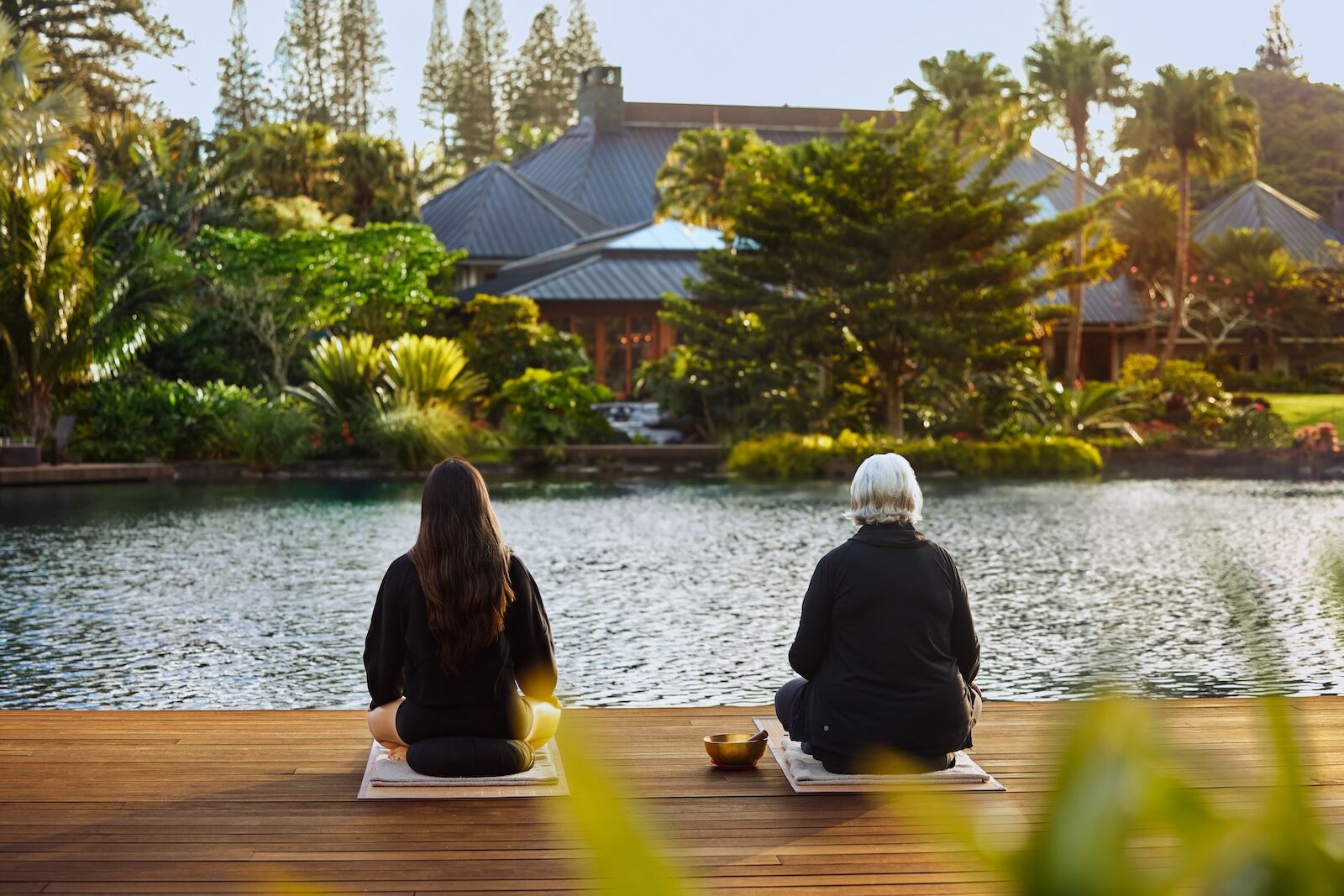 two people meditating near a pond