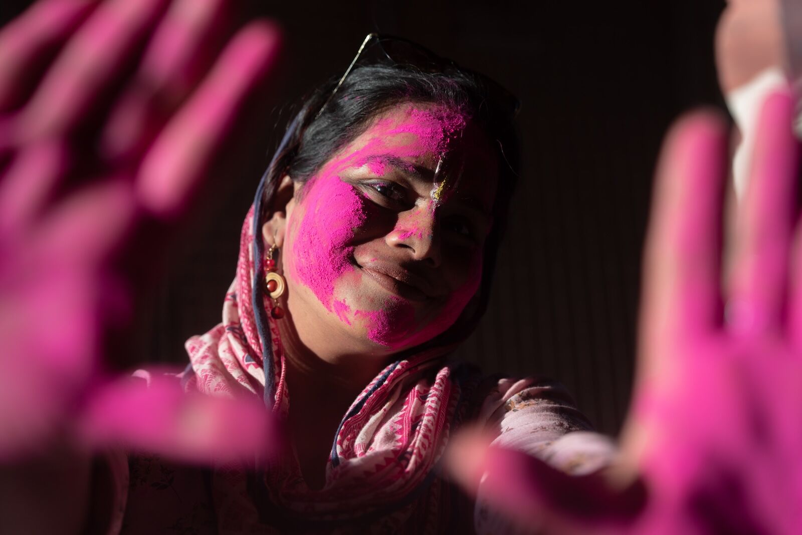 a woman covered in pink powder during holi in india. scene of holi celebrations in india in new film "colors of unity"