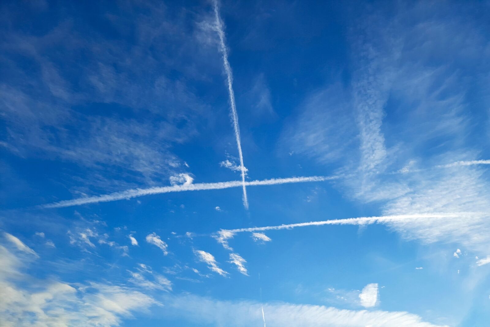 contrails in blue sky with clouds