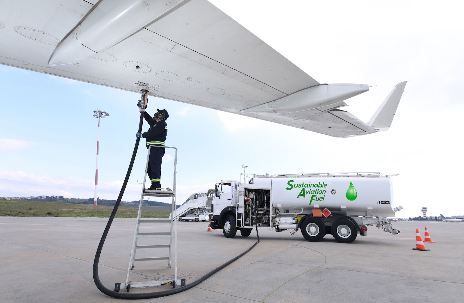 technician fueling airplane with sustainable aviation fuel