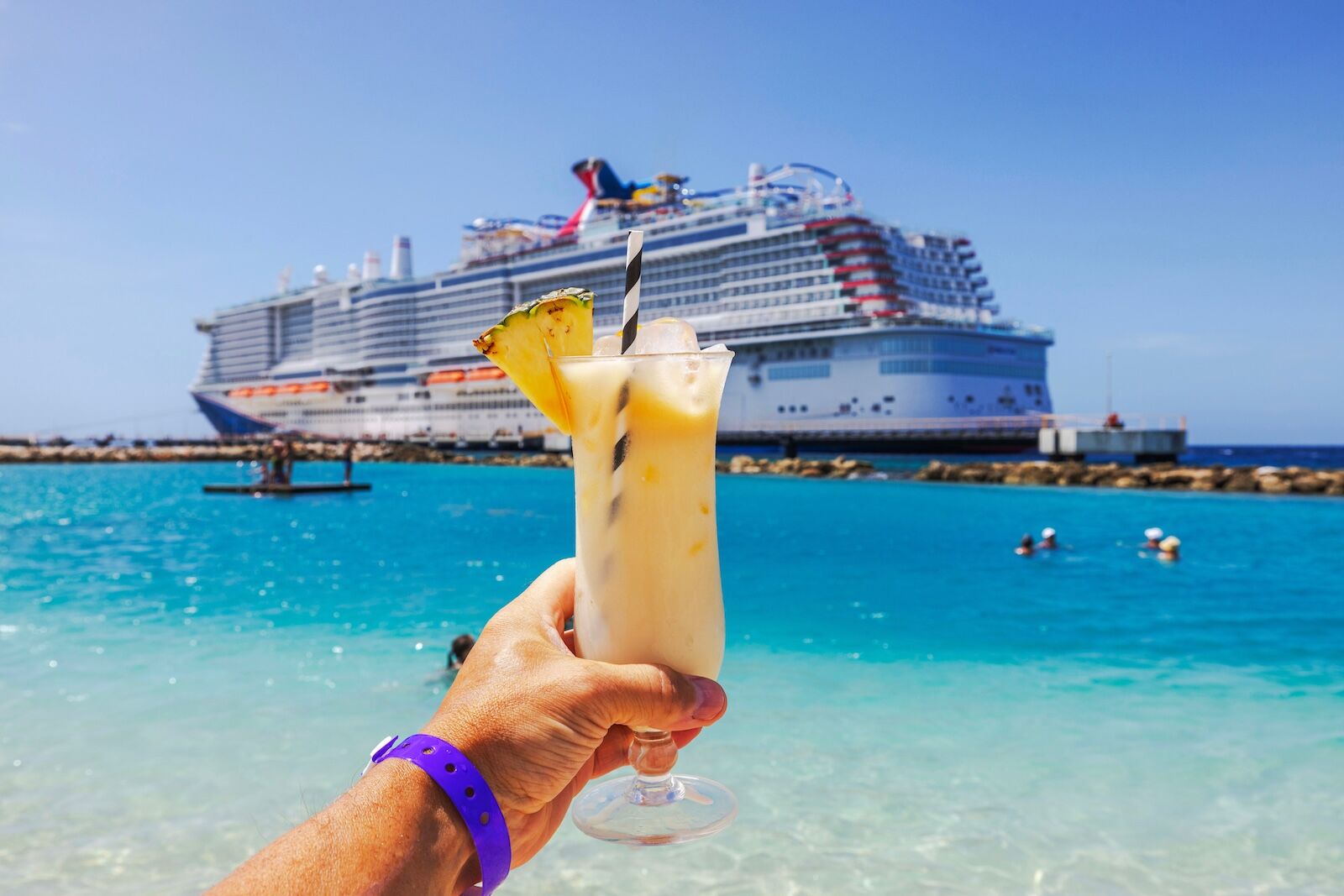 hand holding drink in front of cruise ship