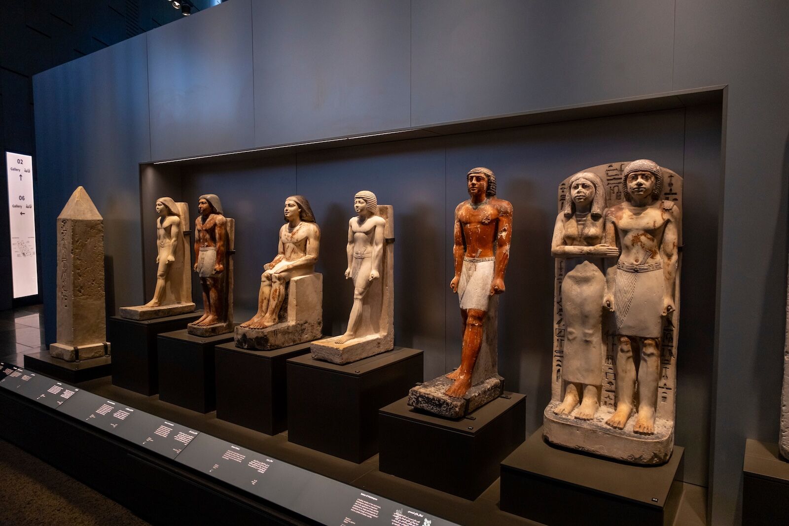 Giza, Egypt. October 2, 2025: A display of various ancient Egyptian statues, including seated and standing figures, showcasing different materials and preserved colors, Grand Egyptian Museum (GEM).
