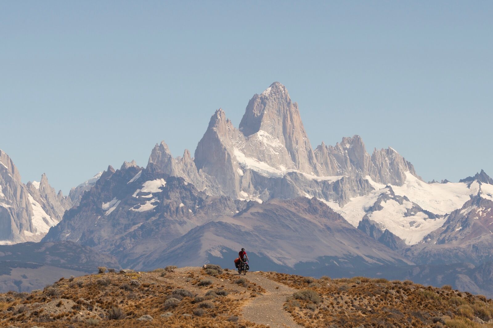 Cyclist bikepacking in front of massive Mount Fitz Roy, Patagonia, Argentina