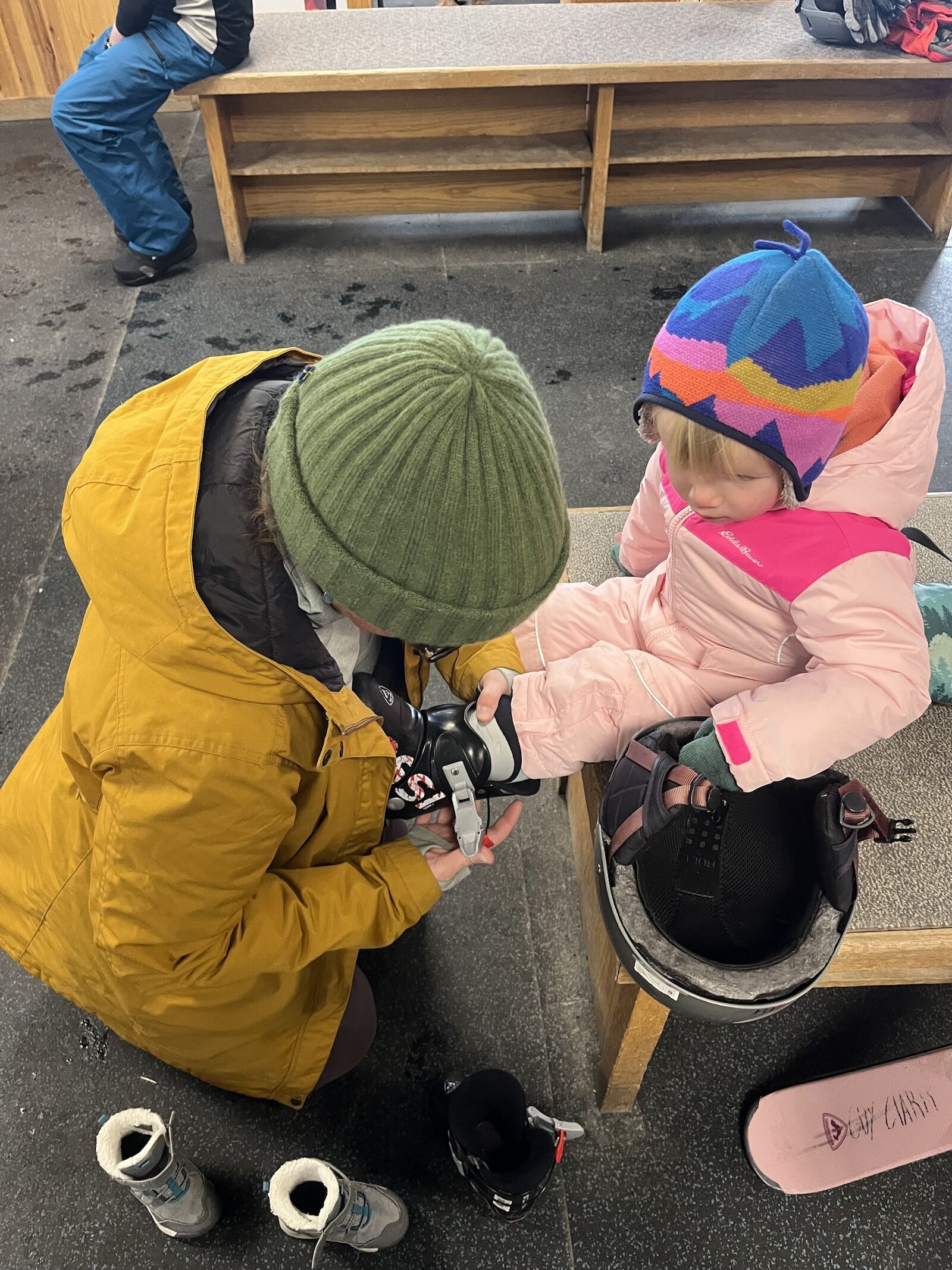 mom dressing toddler in ski gear