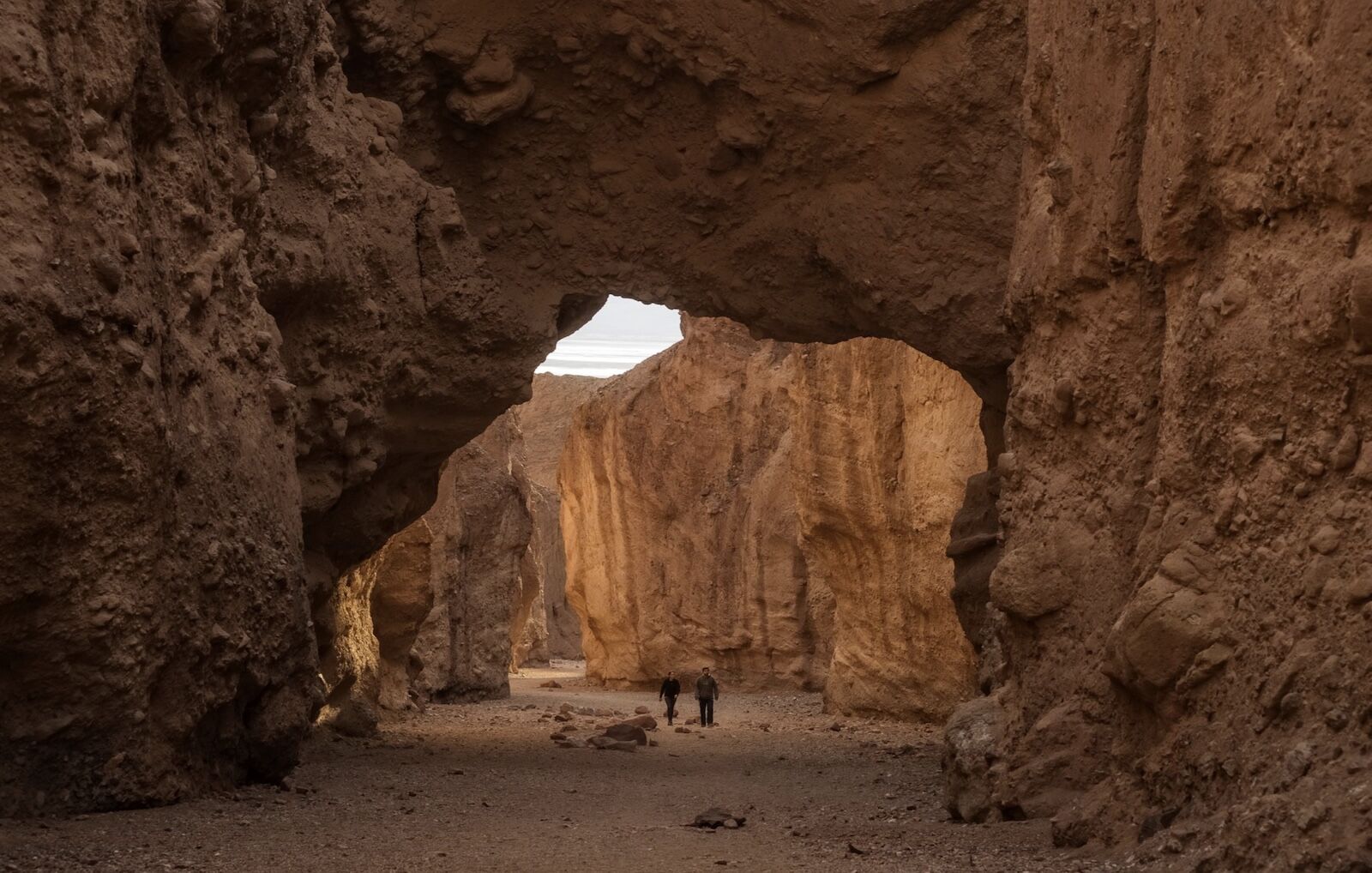 hikers under a natural bridge in death valle np