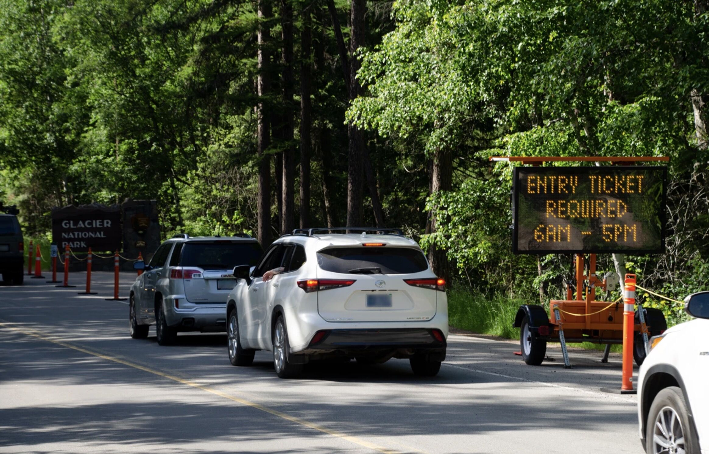 reservations at national parks - cars outside glacier national park with reservations sign