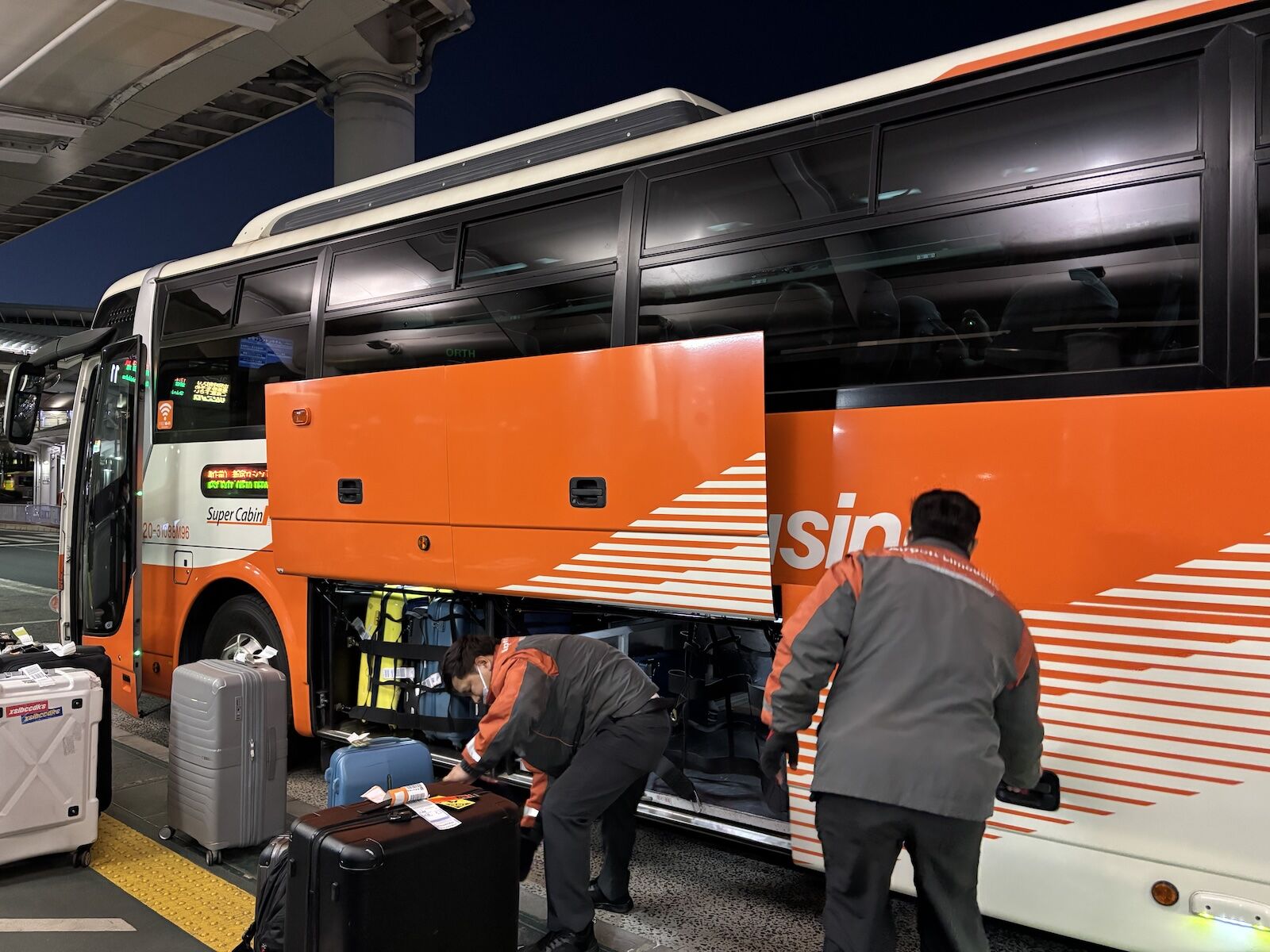 men loading bags onto airport limousine bus in tokyo