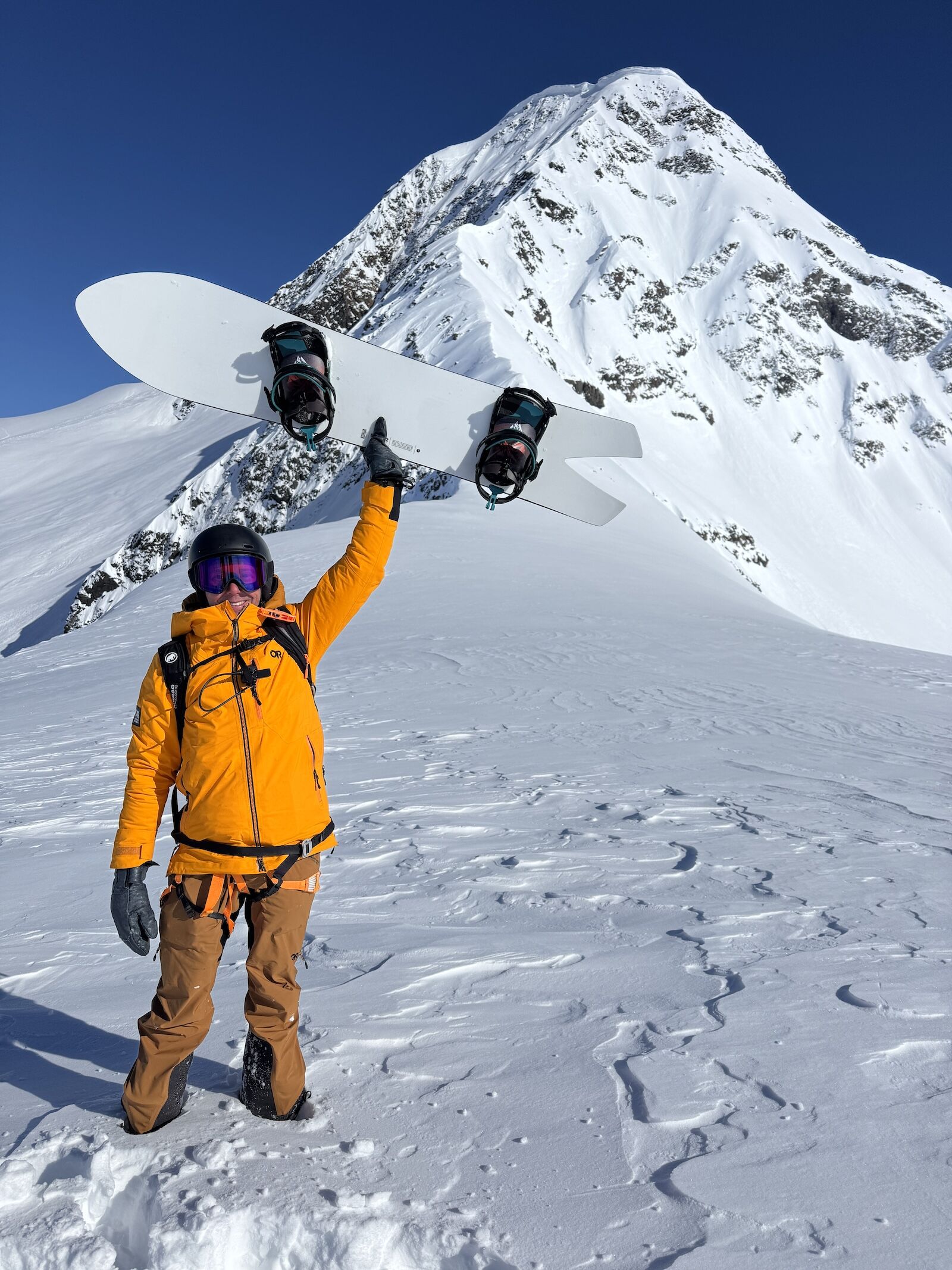 snowboarder holding board in air in alaska mountains